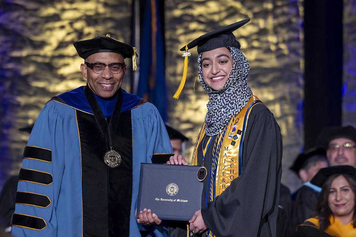 A student receiving her diploma on stage from Chancellor Laurence Alexander.