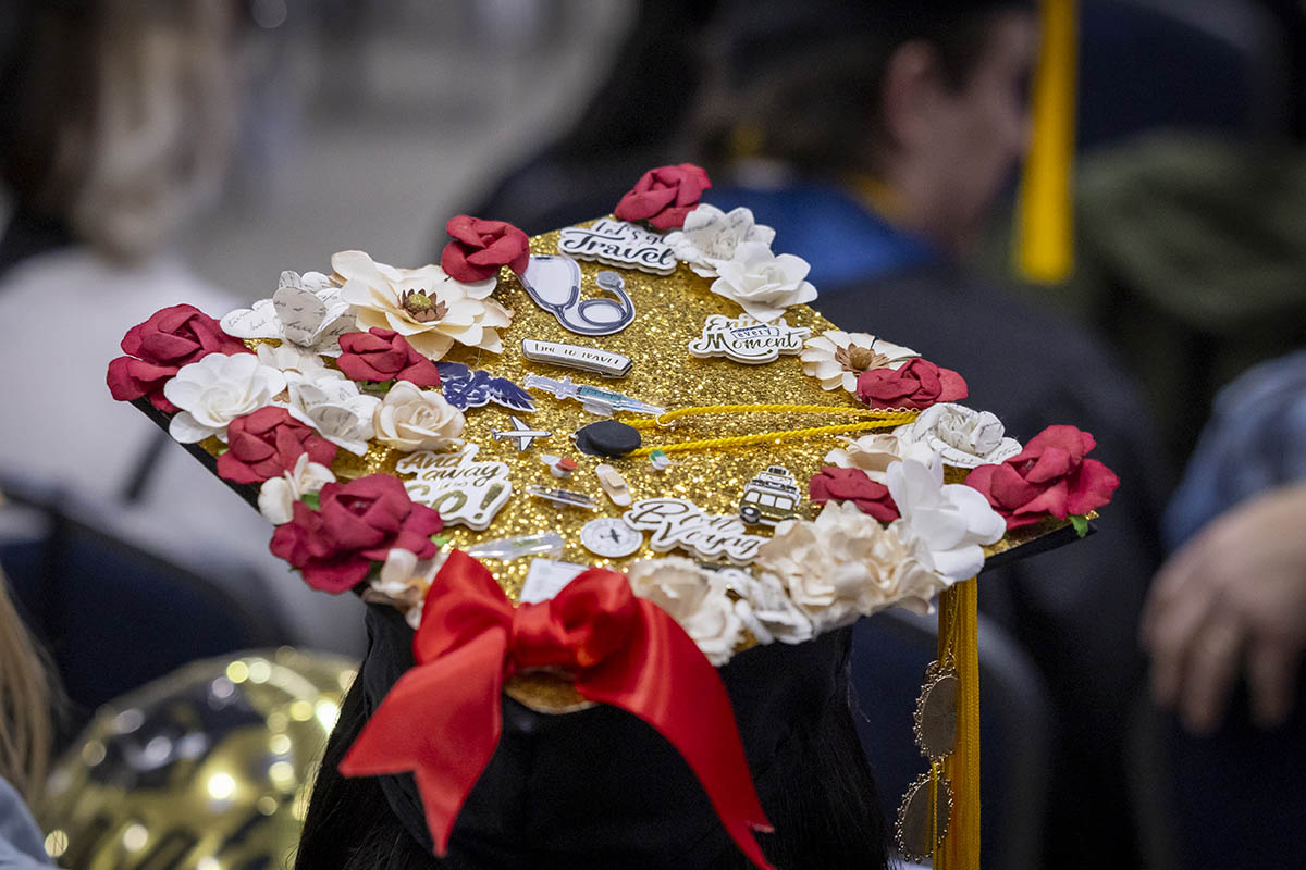 A decorated graduation cap with flowers, pins of planes, bows, etc.
