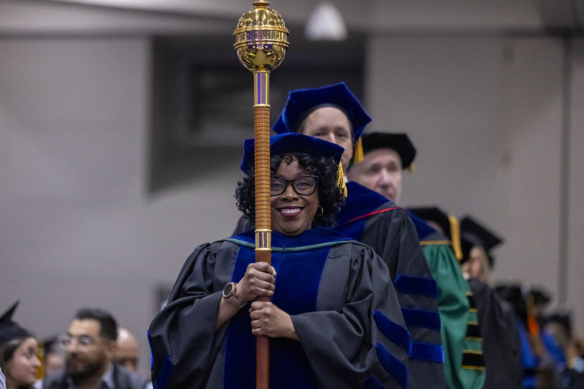 A faculty members processing through the room with a ceremonial mace.