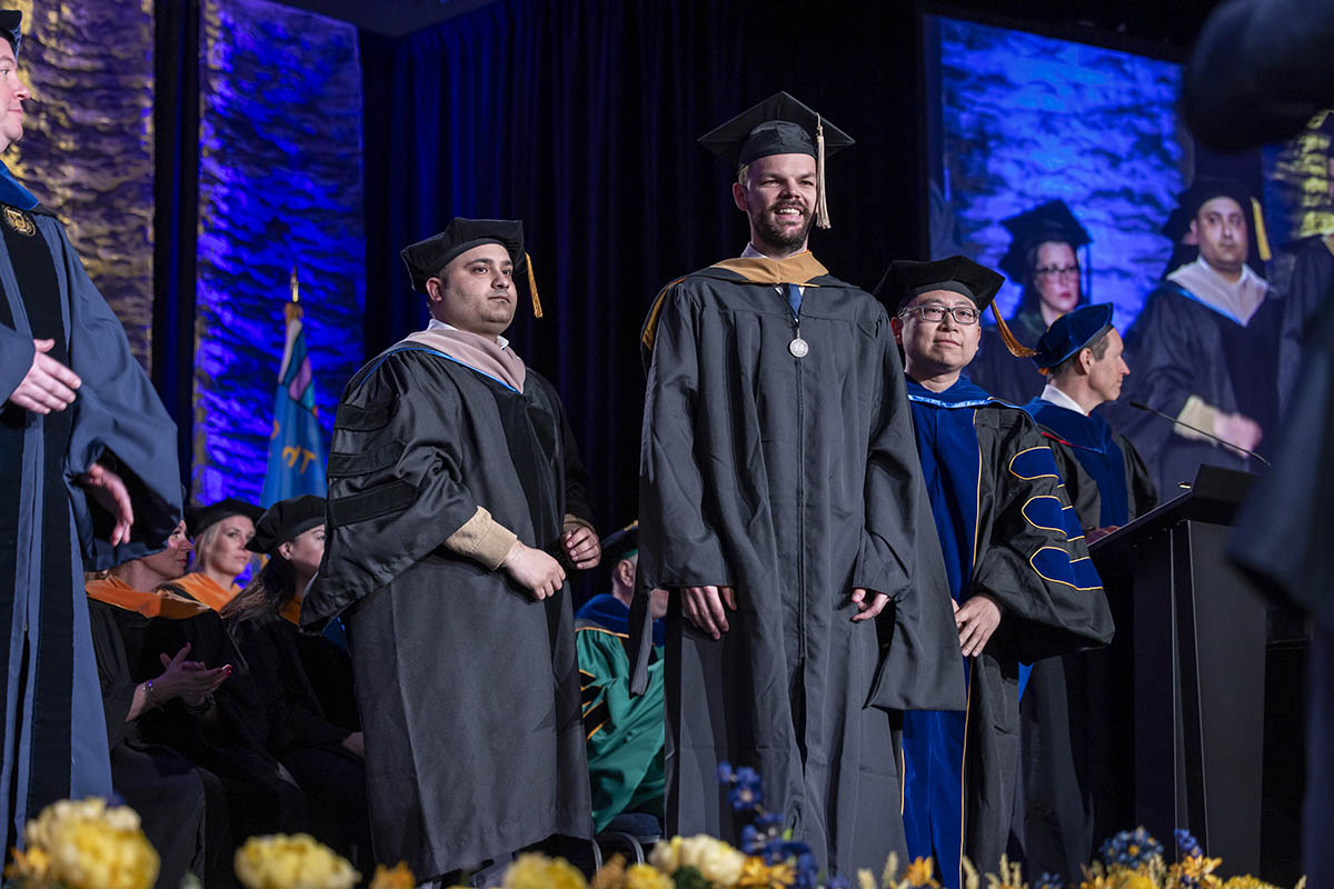 A student receiving his diploma on stage from Chancellor Laurence Alexander.