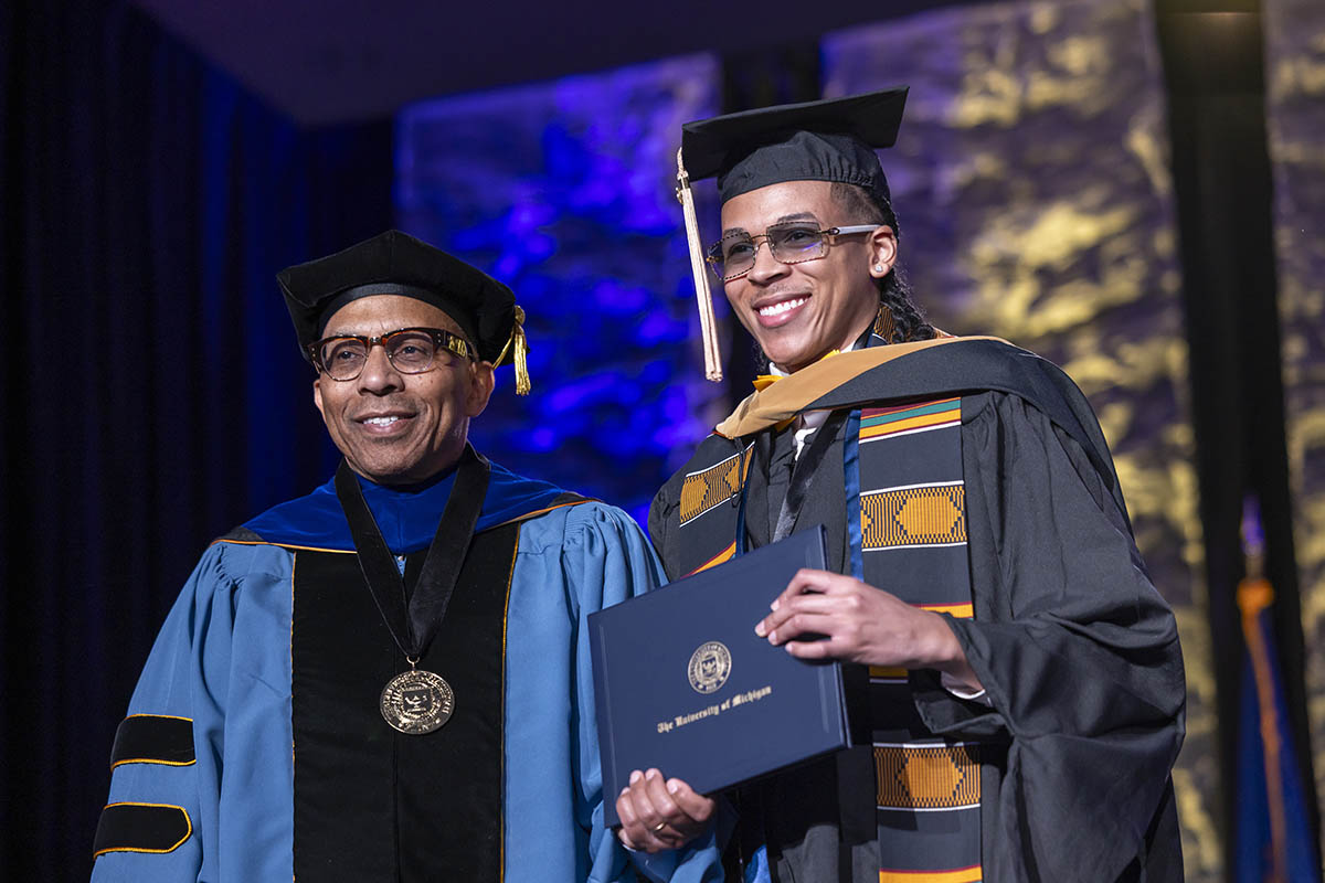A student receiving his diploma on stage from Chancellor Laurence Alexander.