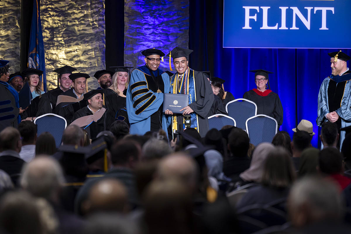 A student receiving his diploma on stage from Chancellor Laurence Alexander.