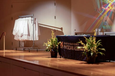 An empty stage at the physician assistant white coat ceremony showcasing a rack of white coats waiting to be distributed.