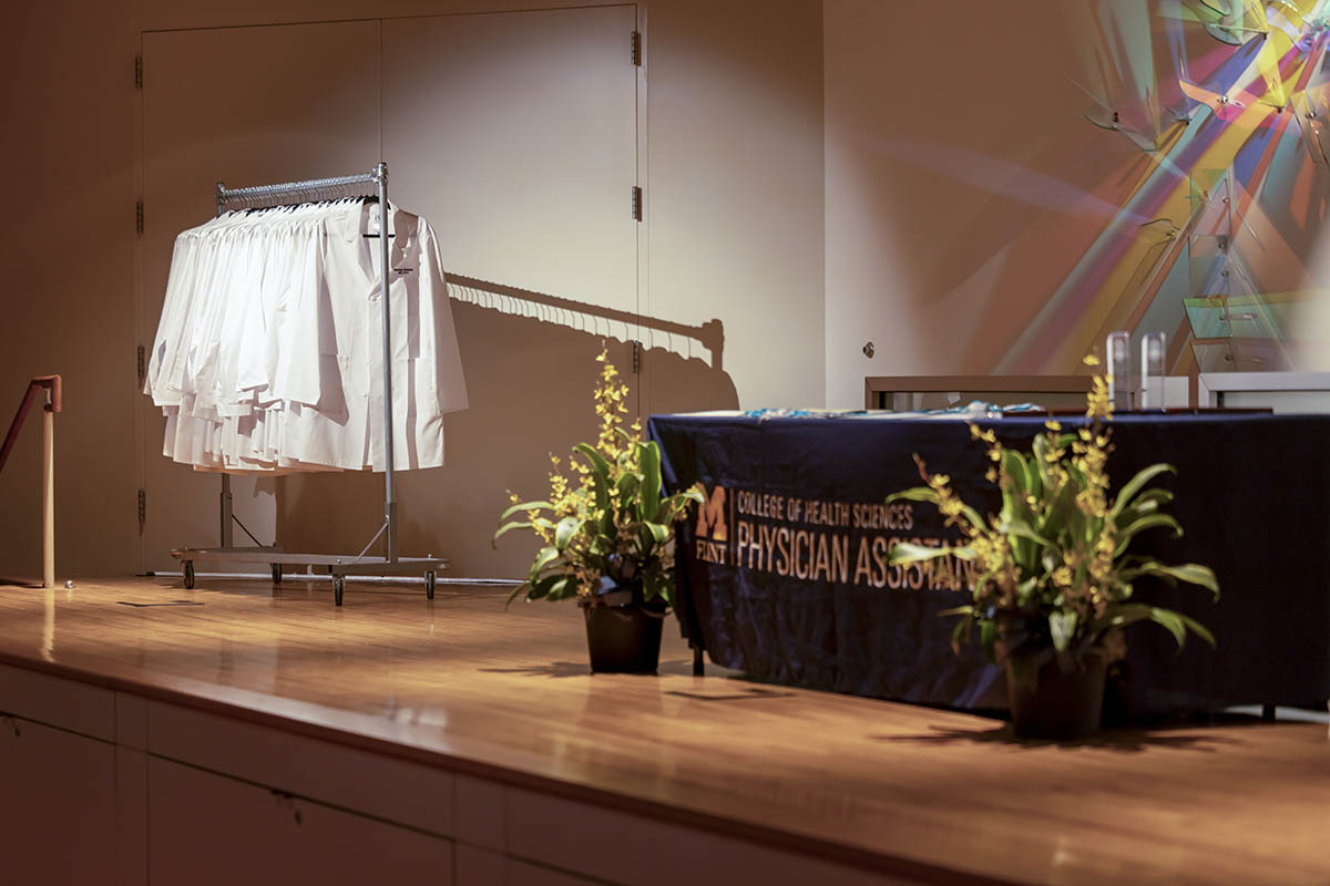 An empty stage at the physician assistant white coat ceremony showcasing a rack of white coats waiting to be distributed.