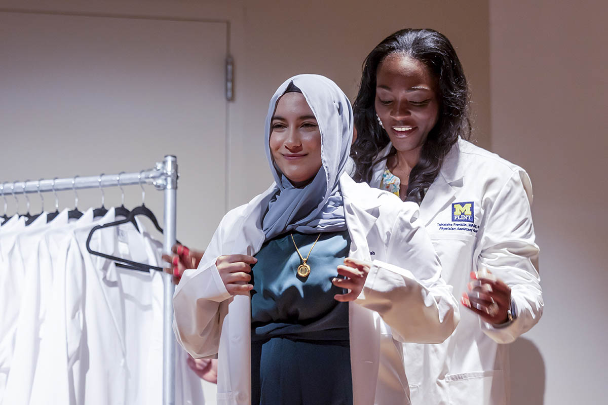 A student receiving her white coat on stage.