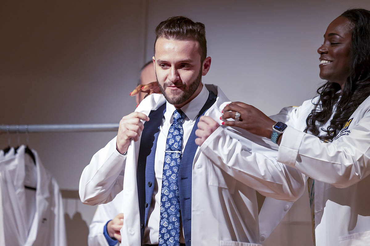 A student receiving his white coat on stage.