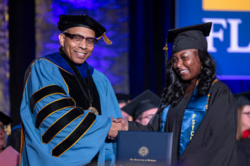 A student receiving her diploma on stage from Chancellor Laurence Alexander
