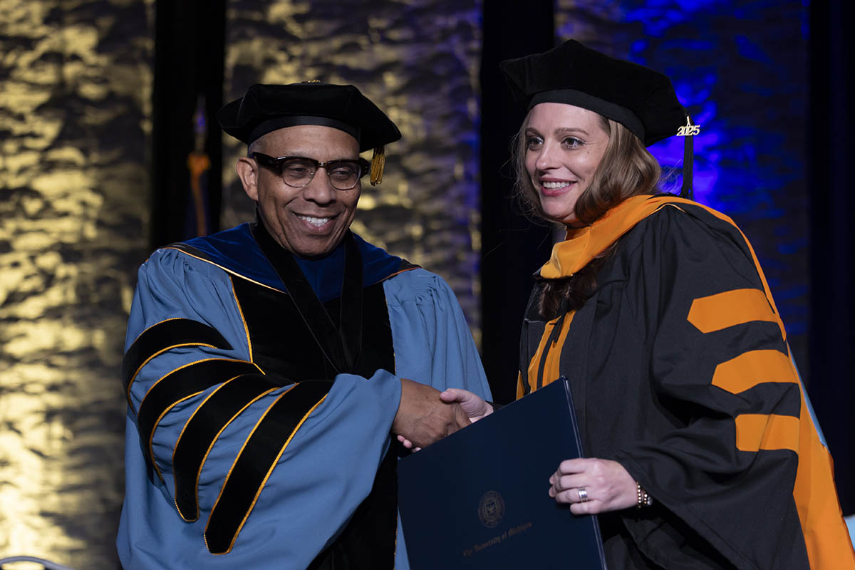 A student shaking hands with Chancellor Alexander receiving her diploma on stage.