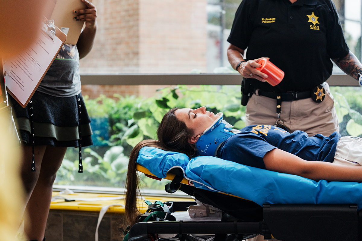 A mock patient on a stretcher with a neck brace