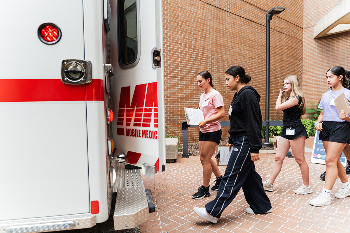 Students walking into the back of an ambulance.