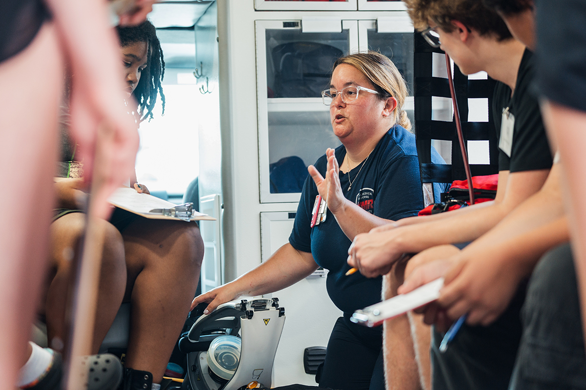 A female EMT speaking to a group of students inside of an ambulance