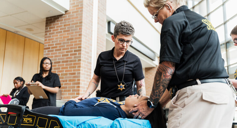 Police officers treating the mock patient on the stretcher.
