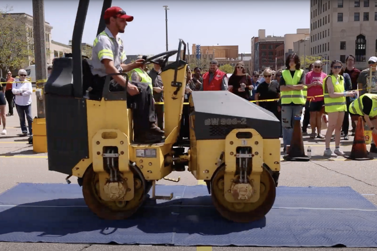 A steamroller rolling over a covered print of art
