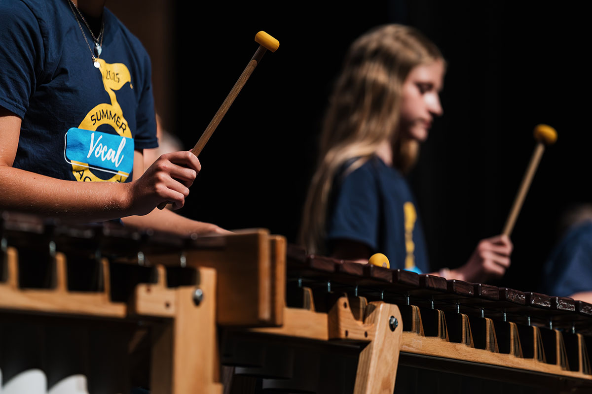 Summer Vocal Academy of Music campers playing a percussion instrument like a xylophone.