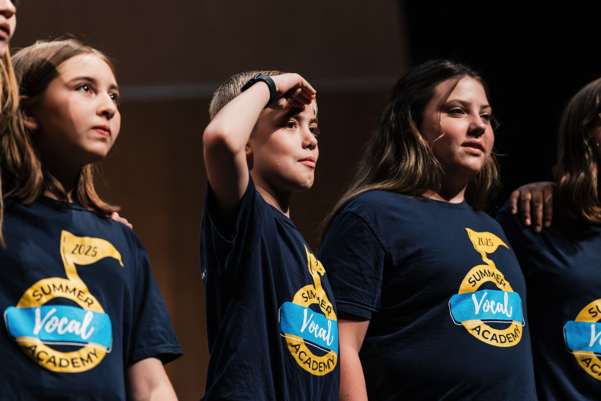Vocalists standing arm in arm on stage.