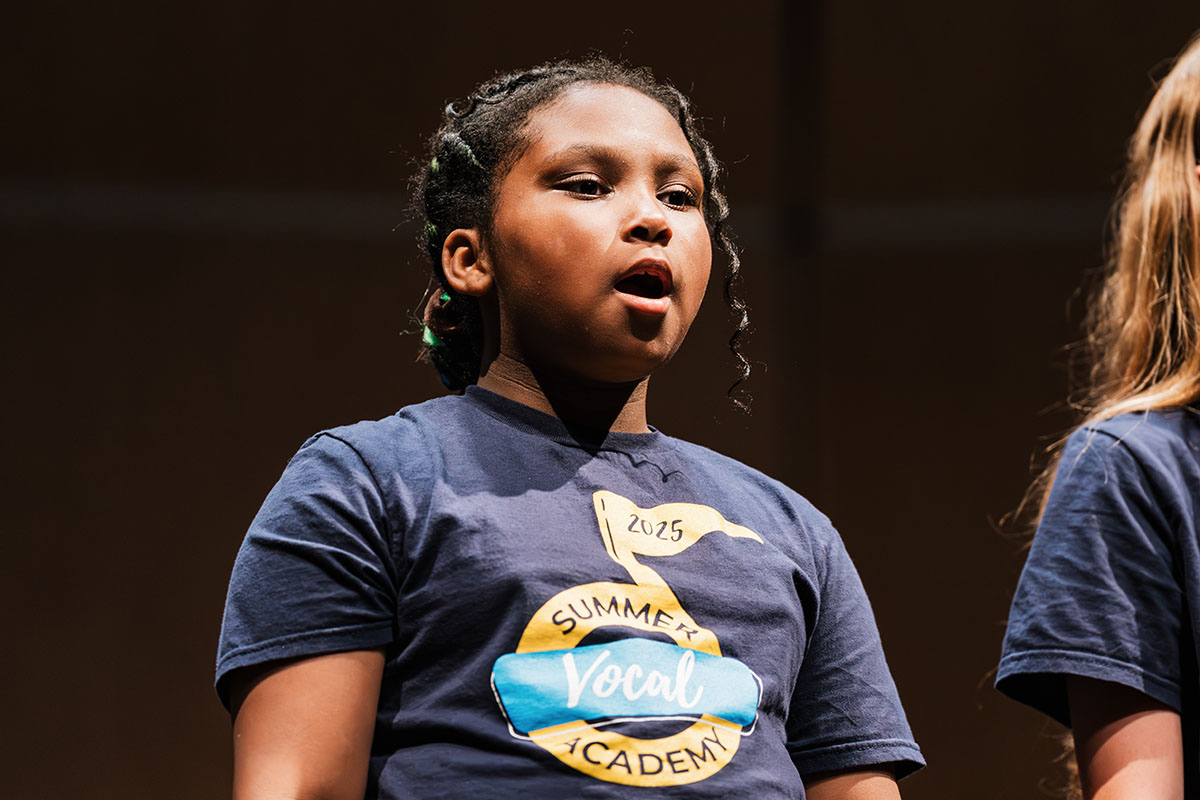A female vocalist singing on stage during the Summer Vocal Academy of Music.