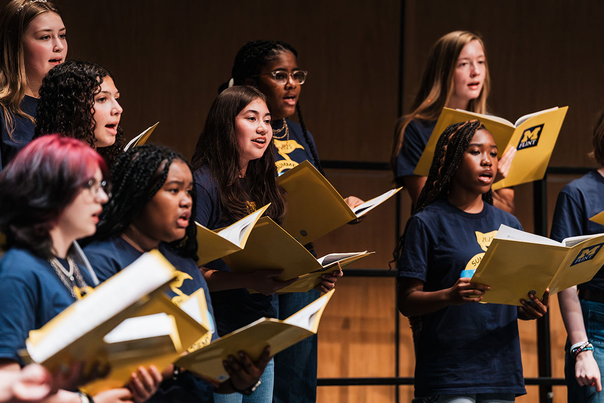 A group of vocalists singing from sheet music during the Summer Vocal Academy of Music.