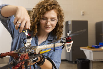 Samantha Hunsinger, a female student, waring safety glasses using tools to fix a drone.
