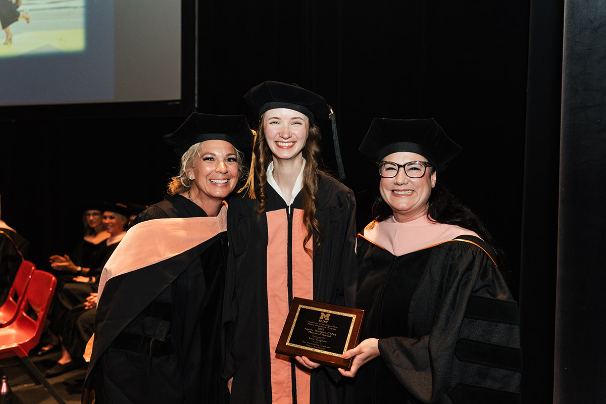 A female DNAP graduate posing with faculty presenting her with an award.