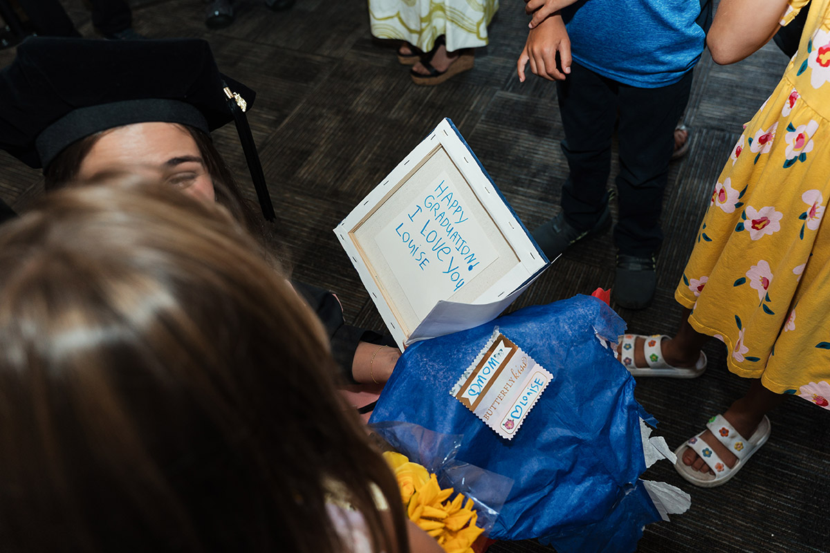 A DNAP graduate reading a handwritten card from a child that reads "Happy graduation I love you, Louise