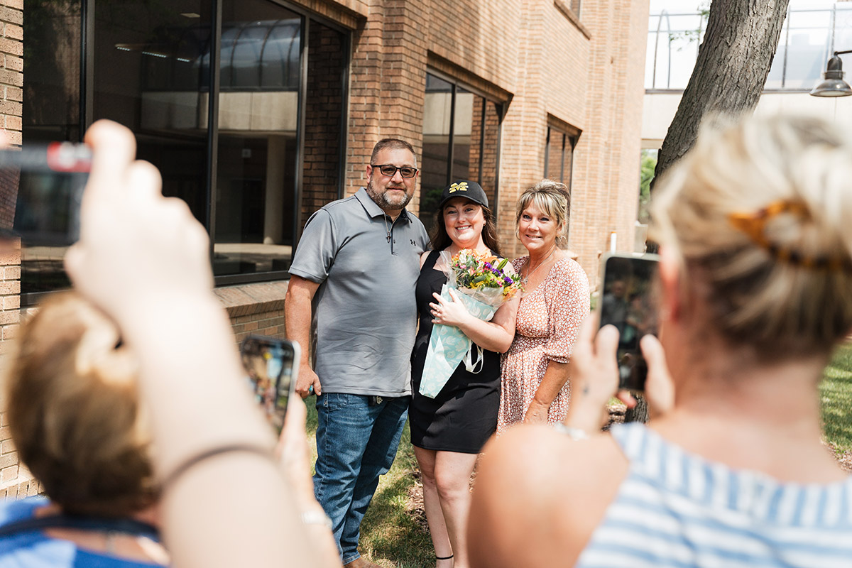 A female DNAP graduate poses for a photo with her mom and dad.