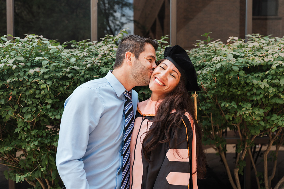 A female DNAP graduates gets a kiss on the cheek from her significant pther.