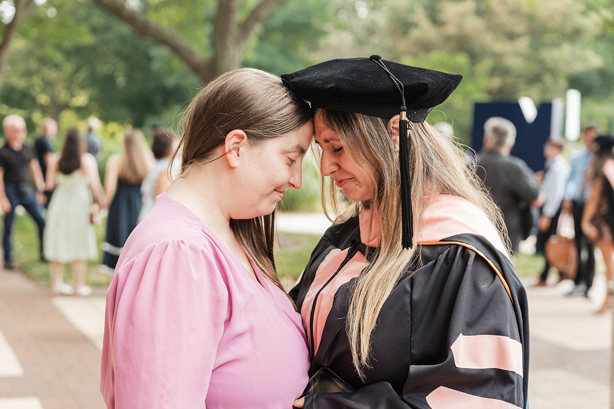 A female dnap graduate touching foreheads with a member of her family