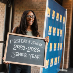 Smiling student holds a chalkboard sign marking the first day of senior year, 2025–2026.