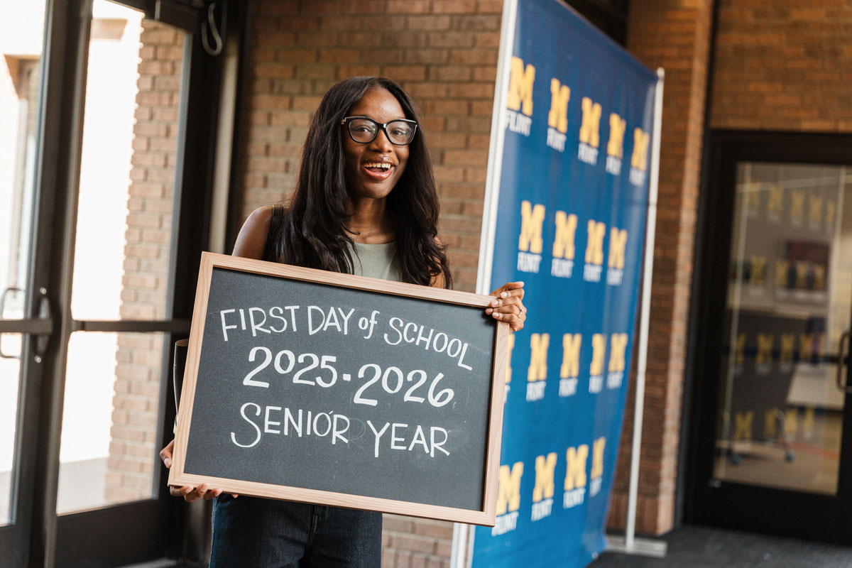 Smiling student holds a chalkboard sign marking the first day of senior year, 2025–2026.