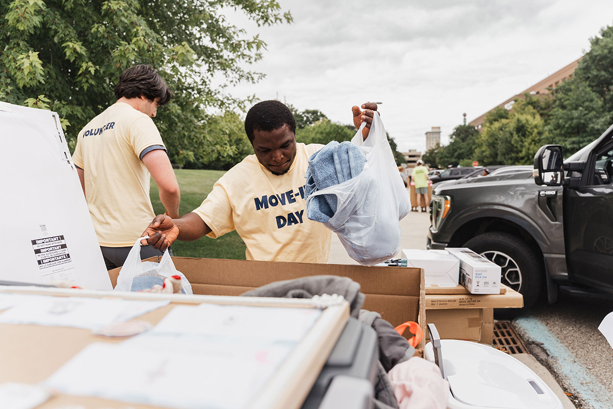 A UM-Flint student volunteer loading bags of clothing into a cart