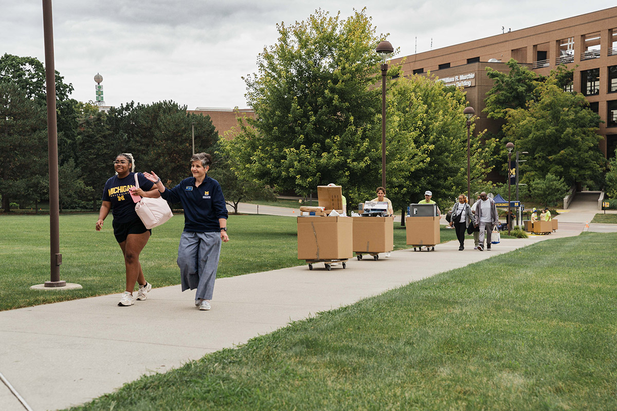 A line of people carting their belongings up the entranceway to First Street Residence Hall