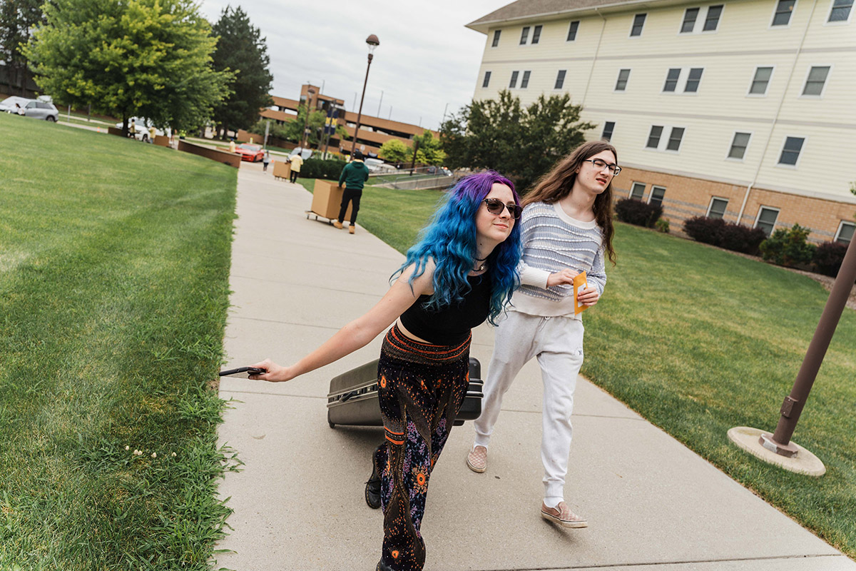 A UM-Flint student wheeling a suitcase inside the dorms.