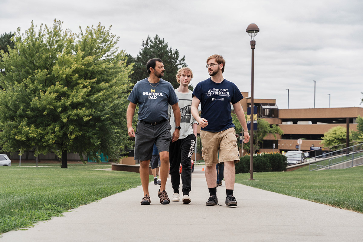 A father and son walk up the entranceway to First Street Residence Hall