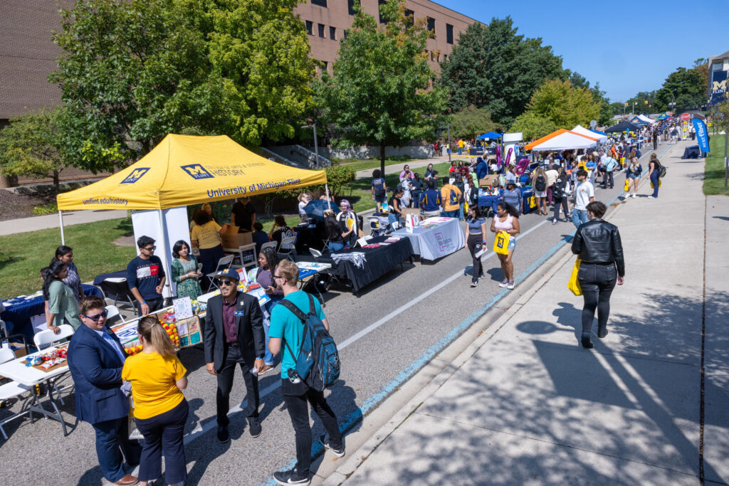 Students hang out and walk around Mgagement on the street outside of two campus buildings.