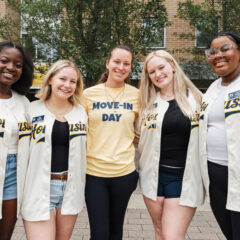 A group of Move-in Volunteers in Maize and Blue Baseball jerseys in front of First Street Residence Hall