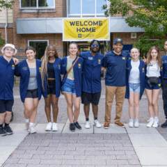 Students and staff stand in front of First Street Residence Hall during move-in.