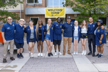 Students and staff stand in front of First Street Residence Hall during move-in.