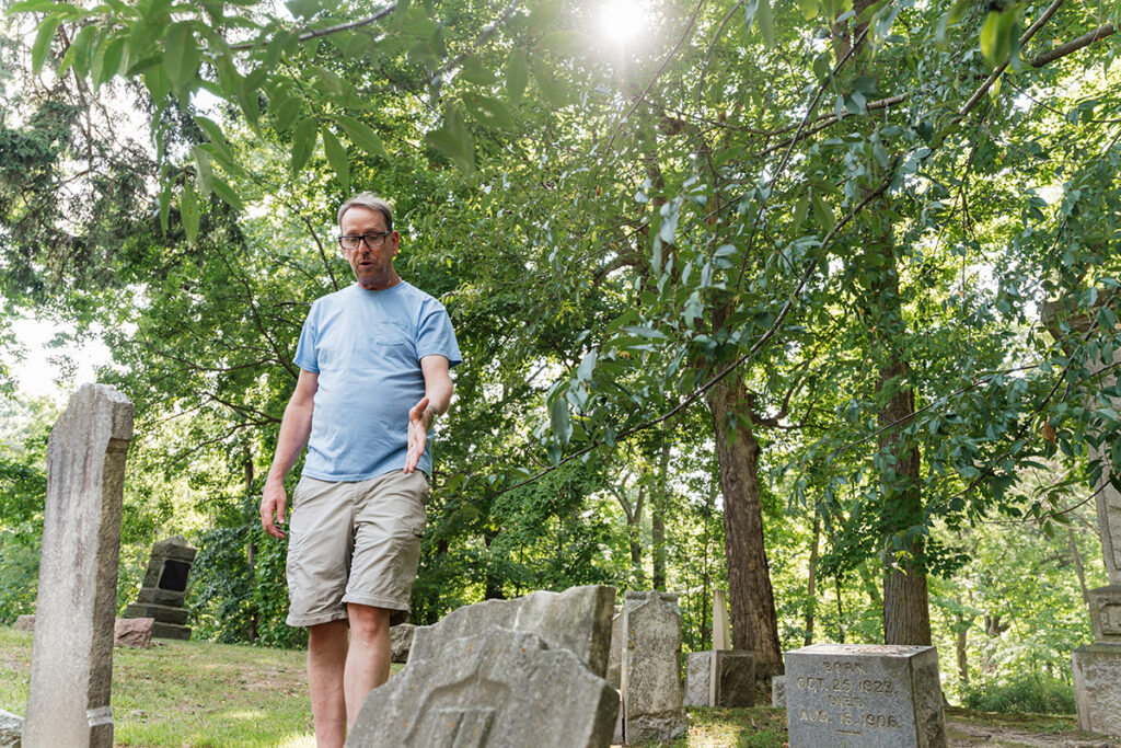 Professor of history Thomas Henthorn talks about a damaged headstone at Glenwood Cemetery in Flint, Michigan on August 15, 2025.