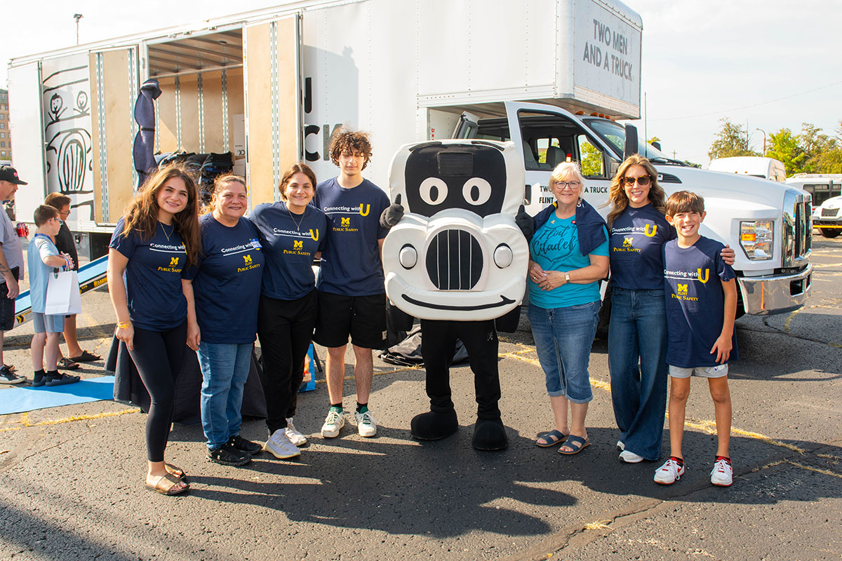 A group of UM-Flint volunteers posing with a truck mascot