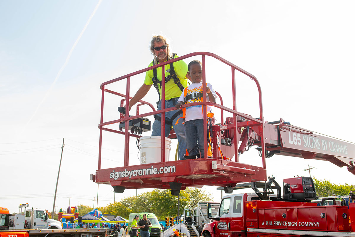 A young boy going up in a cherry picker bucket