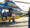 The University of Michigan Survival Flight Helicopter in a parkimg lot. A member of the flight crew is sitting in helicopter, while a mom and son pose for a photo.