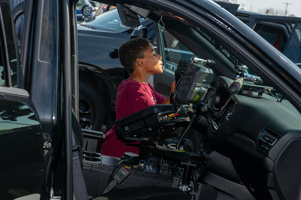A child sitting in the seat of a cop car