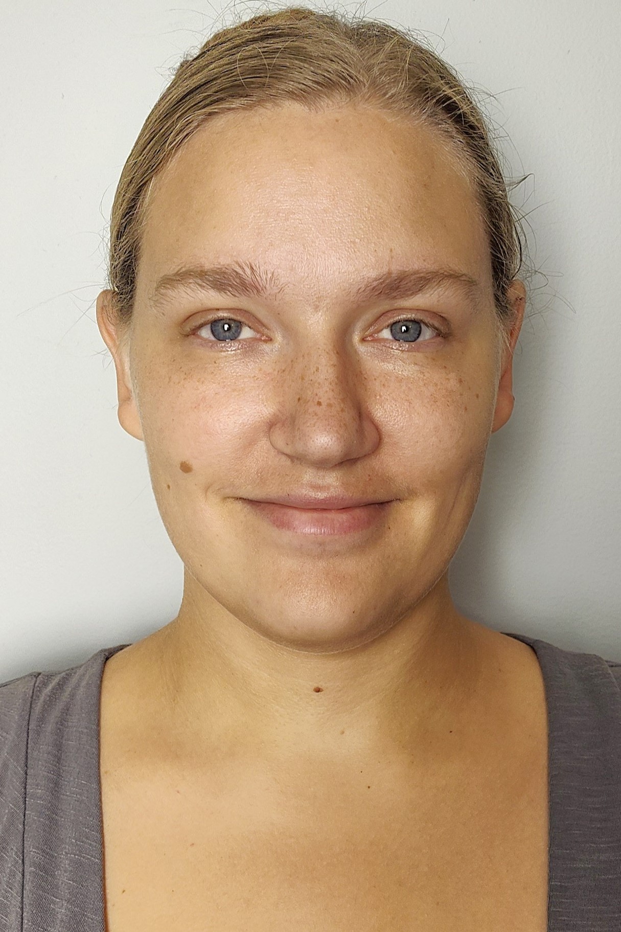 Headshot of a woman with freckles and blue eyes, smiling faintly, with her blonde hair pulled back.