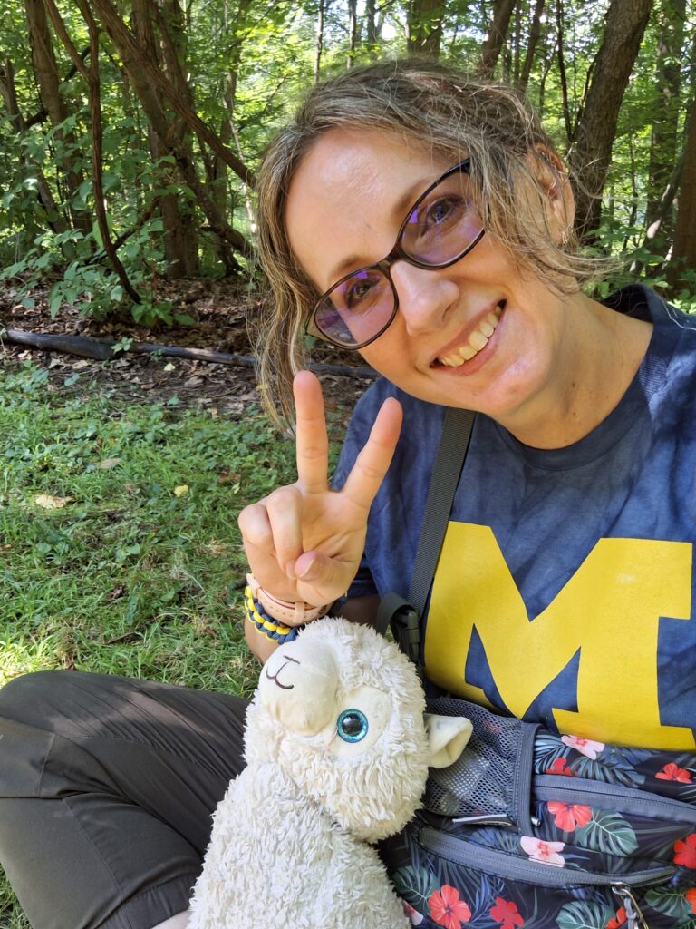 Portrait of Amanda Smith with a stuffed animal and showing a "peace" sign