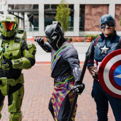Three individuals dressed in superhero costumes: one in green armor, one as Black Panther, and one as Captain America with a shield.