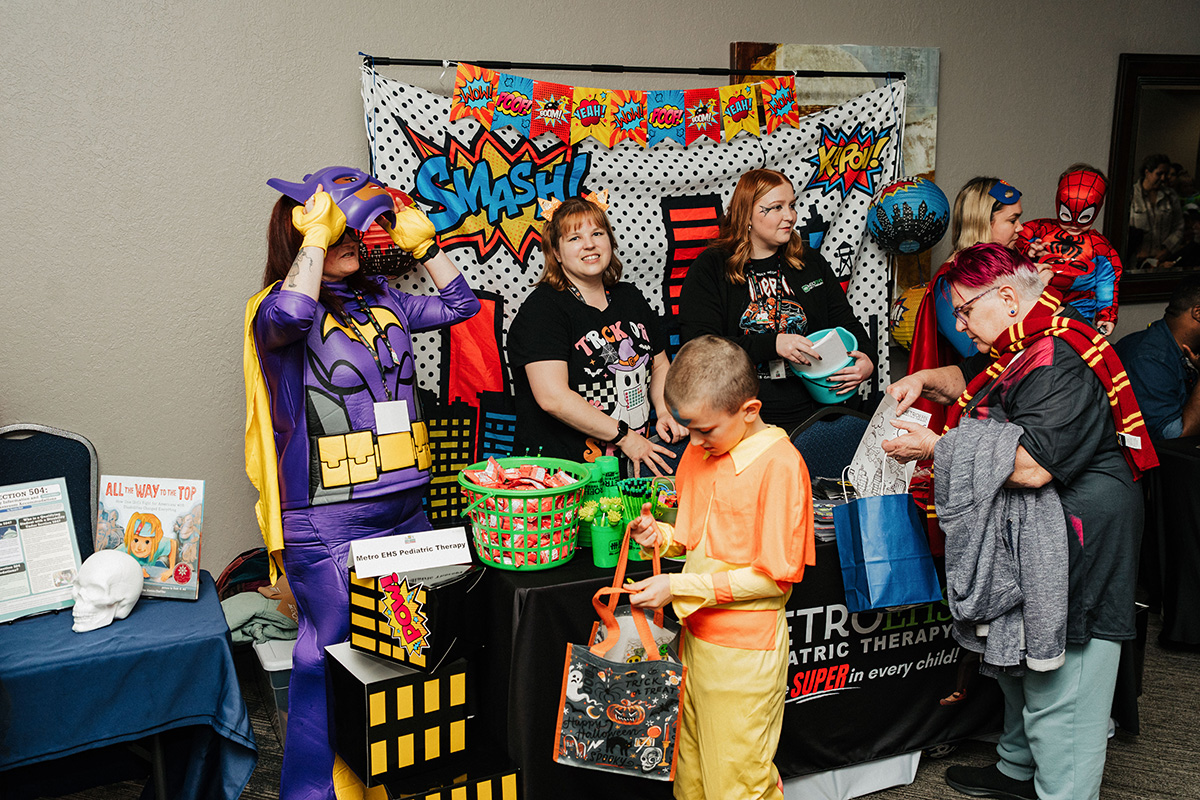 A colorful booth at an event featuring people in costumes, with a banner that says "SMASH!" and various activities for children.