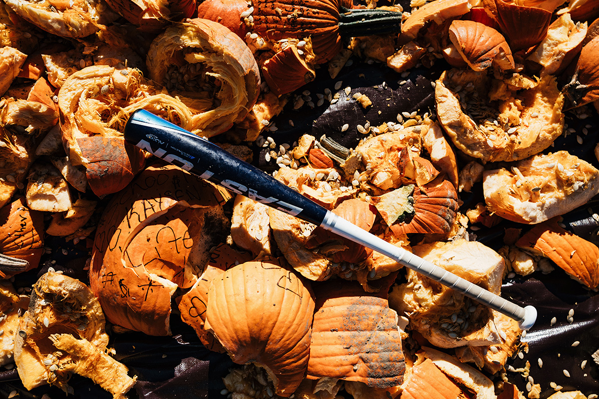 A baseball bat resting on a pile of carved and discarded pumpkin pieces.