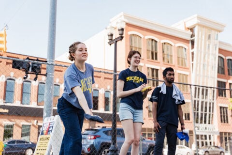 Three people are participating in an outdoor activity, with one person preparing to throw an object while others watch.