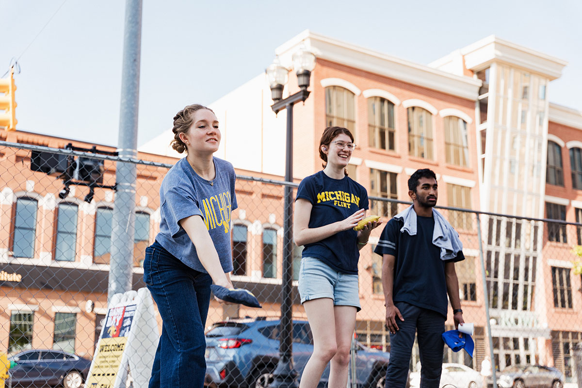Three people are participating in an outdoor activity, with one person preparing to throw an object while others watch.