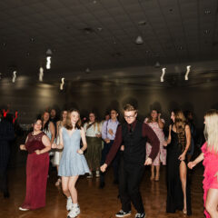 A lively dance floor with people in formal attire enjoying a party, with colorful lights creating a festive atmosphere.
